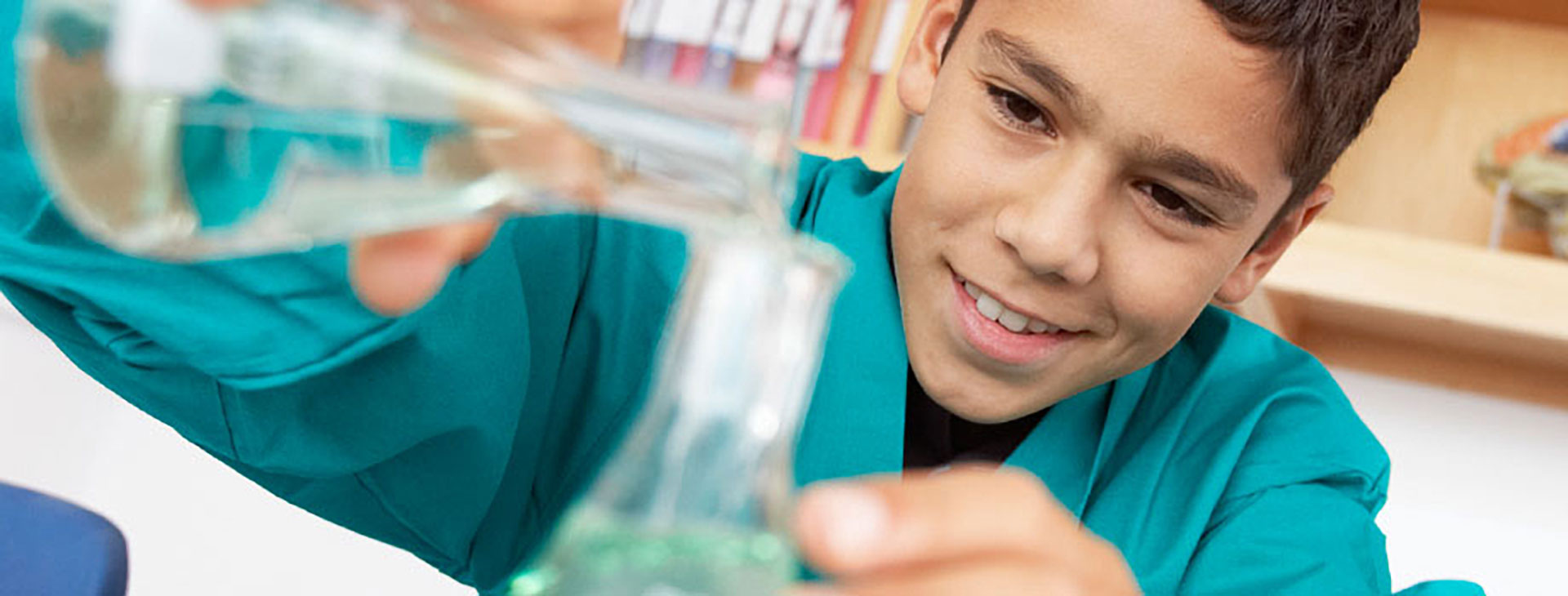 Boy pouring liquid into a test tube.